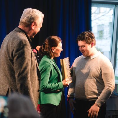 Auszubildender Cyril überreicht Ehrenpreis an WWK Versicherung