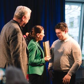 Auszubildender Cyril überreicht Ehrenpreis an WWK Versicherung